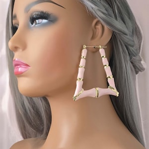 May include: Pink and gold bamboo-style hoop earrings. The earrings are large and have a geometric shape.