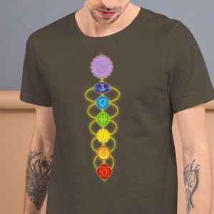 May include: A brown t-shirt with a graphic of the seven chakras, a spiritual concept in Hinduism and Buddhism, represented by colorful circles and a yellow line connecting them.