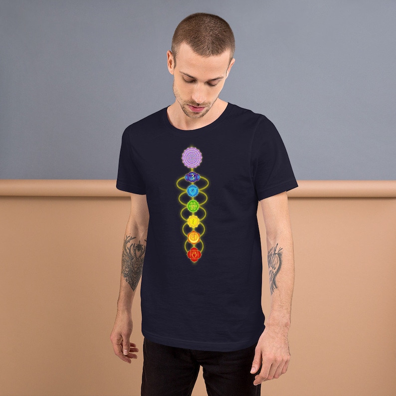 May include: A navy blue t-shirt with a graphic of the seven chakras, a spiritual concept in Hinduism and Buddhism, represented by seven colored circles connected by a golden line.