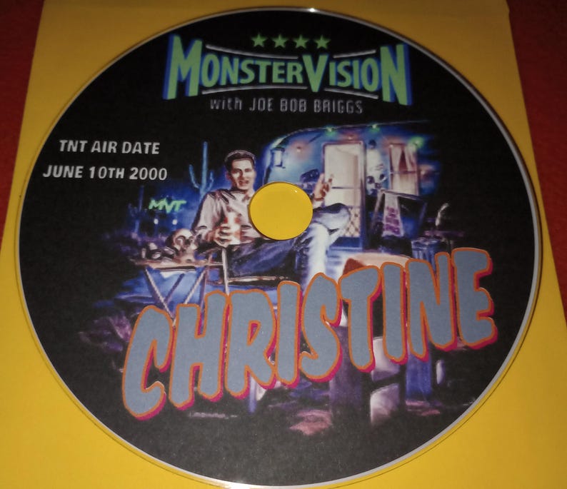K&ouml;nnte beinhalten: Eine DVD-Disc mit schwarzem Hintergrund und einem bunten Bild eines Mannes, der auf einem Stuhl vor einem Wohnwagen sitzt. Der Text "MonsterVision with Joe Bob Briggs" befindet sich oben auf der Disc. Der Text "TNT Air Date June 10th 2000" befindet sich unten links auf der Disc. Der Text "Christine" ist in gro&szlig;en, fetten, blauen Buchstaben mit roter Umrandung in der Mitte der Disc.