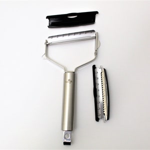 May include: A silver peeler with a black handle and a removable blade. The peeler has a black plastic cover and a black plastic blade holder.
