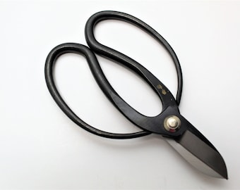 May include: Black pruning shears with a silver rivet and a gold inscription. The shears have a curved handle and a sharp blade.