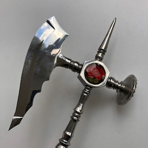 May include: A silver axe with a decorative rose design on the handle. The axe has a sharp blade and a pointed tip.
