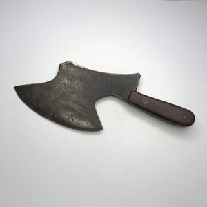 May include: A vintage, rusty, metal axe with a brown wooden handle. The axe has a curved blade and a rounded head.