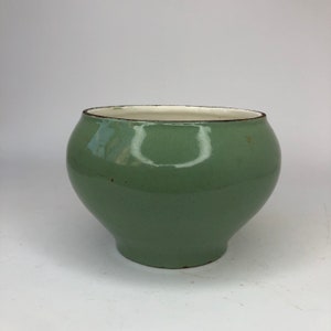 May include: A green ceramic pot with a rounded bottom and a white rim.