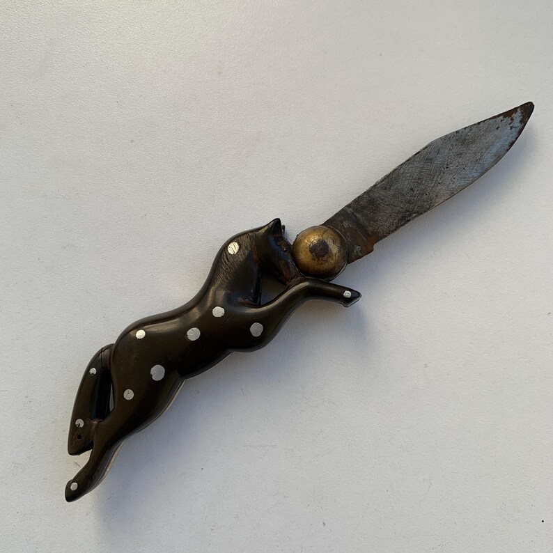 Puede incluir: Un cuchillo de bolsillo negro y blanco con manchas con un mango en forma de caballo. La hoja est&aacute; abierta y el mango est&aacute; hecho de un material oscuro con puntos blancos.