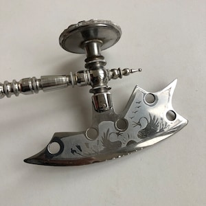 May include: A silver-toned metal axe with a decorative handle and a blade etched with a bird and floral design.