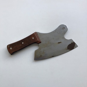 May include: A brown-handled cleaver with a metal blade. The blade is curved and has a small hole near the handle.
