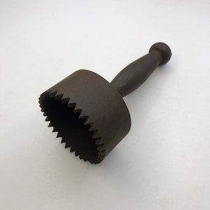 Könnte beinhalten: Ein braunes Metallwerkzeug mit einem Griff und einer gezahnten kreisförmigen Klinge. Das Werkzeug wird zum Ausschneiden von Formen aus Materialien wie Leder oder Stoff verwendet.