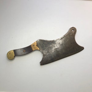 May include: A vintage butcher knife with a brown wooden handle and brass accents. The blade is curved and has a worn, aged appearance.