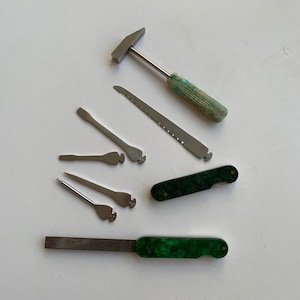 Könnte beinhalten: Ein Satz Werkzeuge mit einem grünen Griff, einem kleinen Hammer, einer Säge, einer Feile und ein paar anderen Werkzeugen.