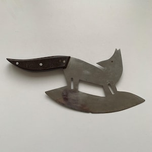 May include: A silver kitchen knife with a brown plastic handle shaped like a fox. The knife has a curved blade and a fox-shaped cutout in the blade.