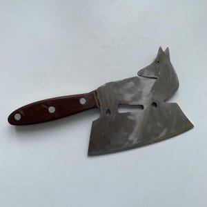 May include: A brown-handled cleaver with a unique, stylized fox design on the blade. The blade is made of stainless steel and has a sharp edge.