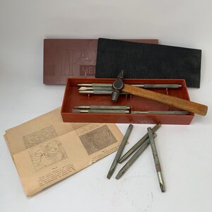 May include: A metal chasing and repoussé tool set featuring a small hammer with a wooden handle, several steel punches, a red plastic storage tray, a dark brown lid with Cyrillic text, and an instructional paper sheet with line art illustrations.