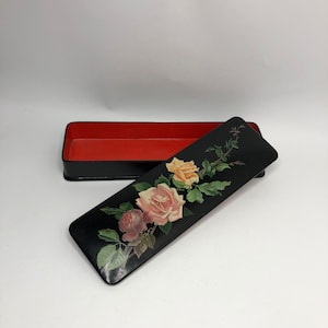 May include: Black lacquered box with a red interior and a floral design on the lid. The lid features a painted design of pink, yellow, and white roses with green leaves.