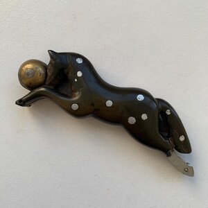 Puede incluir: Una figurita de caballo de madera negra y blanca con manchas blancas y una bola dorada en la boca. El caballo est&aacute; en una pose de carrera con la cola levantada.
