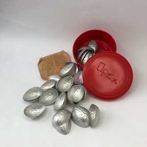 Könnte beinhalten: Ein Set mit 18 silberfarbenen Nussknacker-Schalen aus Metall in einem roten Plastikbehälter mit dem Wort "Opex" auf dem Deckel. Der Behälter ist geöffnet und die Schalen liegen verstreut herum.