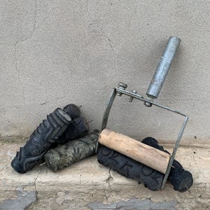 May include: A metal paint roller frame with a wooden handle and a patterned rubber roller attachment, accompanied by two additional black rubber rollers featuring intricate embossed designs for decorative wall painting applications.