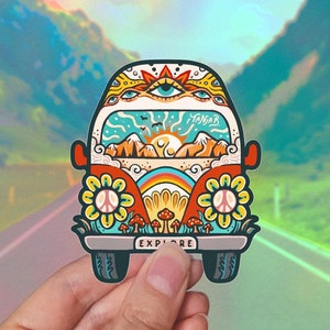 Può includere: Un adesivo di furgone psichedelico colorato con un arcobaleno, simboli di pace, fiori e funghi. Il furgone ha un finestrino con una scena di montagna e la parola "Tanjab" scritta su di esso. L'adesivo dice "Esplora" in basso.