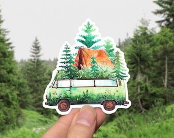 Op de afbeelding: Een groene vintage bus met een bruine tent en groene bomen op het dak. De bus is omringd door groen gras en bomen.