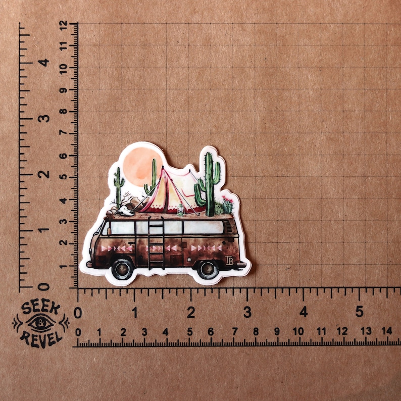 May include: A vintage camper van with a red and white tent on top, surrounded by cacti and a sunset in the background. The van is brown with a ladder on the side and the text "TB" on the back.