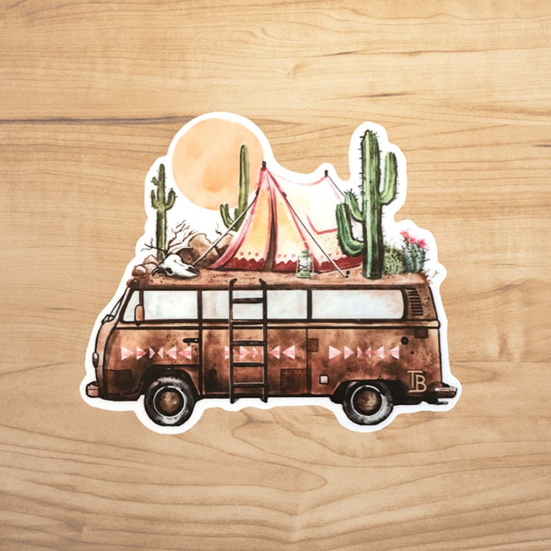 May include: A vintage brown camper van with a ladder on the side, decorated with a pink and yellow tent, a skull, and cacti on the roof. The van has a white outline and the letters "TB" on the side.