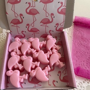 May include: A pink gift box with a flamingo print and a pink organza bag. The box contains 12 pink flamingo shaped wax melts. The box has a "Handmade" label.