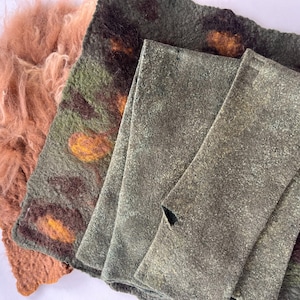 Puede incluir: Un surtido de textiles de fieltro hechos a mano en tonos tierra. La imagen presenta una pieza esponjosa de color melocotón, una pieza estampada en verde y marrón y dos piezas grises texturizadas dobladas. Los textiles parecen estar hechos de fibras naturales.