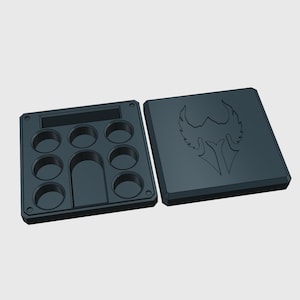 May include: A black plastic box with a lid. The box has eight round compartments and a rectangular compartment. The lid has a black and white graphic of a winged creature with a helmet.