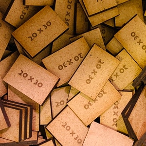 May include: A close-up of a pile of wooden tiles with the text "20 x 30" printed on them. The tiles are arranged in a random pattern and are all the same size.