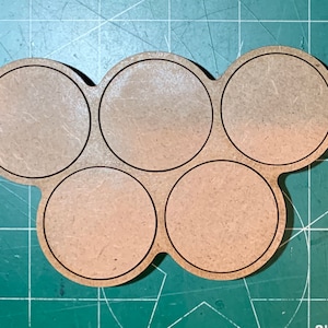 May include: A wooden paint pot holder with six circular compartments. The holder is brown and has a natural wood finish.