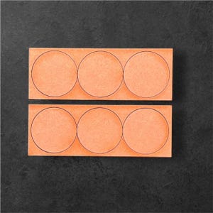 May include: Two rows of six orange paper circles with black outlines. The circles are arranged in a rectangular shape.