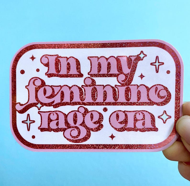 May include: Pink and white sticker with glitter and the text "In my feminine rage era".