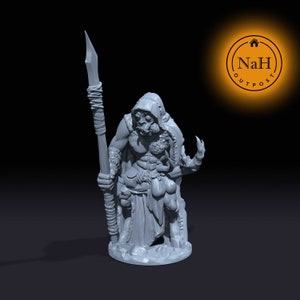 May include: A gray 3D printed miniature of a humanoid figure with a spear, wearing a hooded cloak and holding a claw in its other hand. The figure is standing on a rocky base.