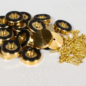 May include: A set of gold-colored speaker isolation feet with black rubber inserts and a pile of gold-colored screws.