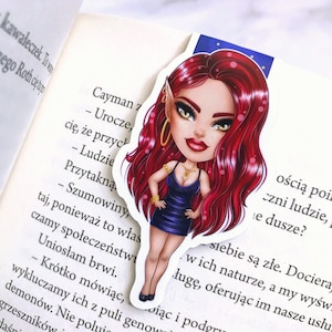 Puede incluir: Una pegatina con una ilustración de dibujos animados de una mujer con cabello rojo, vistiendo un vestido azul y joyas de oro. El fondo es un cielo azul con estrellas.