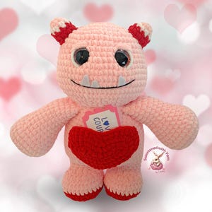 May include: Pink crocheted monster holding a red crocheted heart with a tag that says "Love Coup".