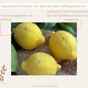 May include: Three bright yellow lemon-shaped decorative objects with textured surfaces. The lemons have small, light-colored accents and are surrounded by green leaves. The image includes text in German: "Das perfekte Geschenk..." and the website "www.manufaktur-loewe.de".