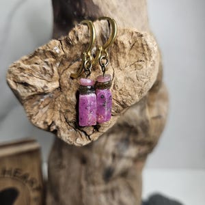 May include: A pair of earrings with pink and gray stone accents hanging from gold hoops.
