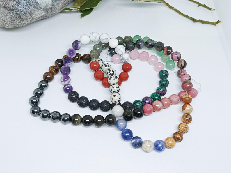 Pode incluir: Uma cole&ccedil;&atilde;o de pulseiras de contas em v&aacute;rias cores e tipos de pedra. As pulseiras incluem contas em tons de preto, castanho, roxo, branco, vermelho, rosa, verde e azul. As contas s&atilde;o enfiadas em cord&otilde;es el&aacute;sticos.