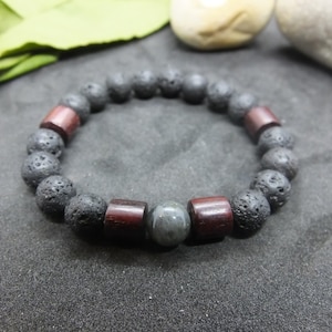 Peut inclure: Un bracelet en perles de lave noire et de bois avec une perle de pierre précieuse grise.
