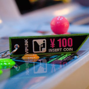 May include: A green and black keychain with the text "VIPLINK" and "¥100 INSERT COIN" in pink and white lettering.