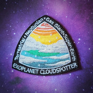 Puede incluir: Parche bordado en blanco y negro con una ilustración colorida de un planeta con anillos. El texto "Exoplanet Cloudspotter" está escrito en la parte inferior del parche. El texto "Terrestrial, Neptunian, Gas Giant, Super-Earth" está escrito alrededor del planeta.