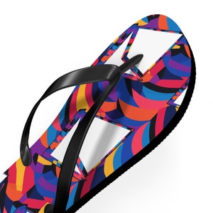 May include: A pair of black flip-flops with a colorful abstract pattern. The pattern features swirls of blue, red, orange, yellow, and purple.