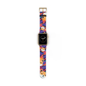 May include: A gold Apple Watch with a colorful band featuring a repeating pattern of Shiba Inu dog faces. The band is made of silicone and has a gold buckle.