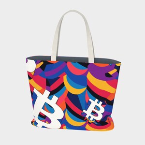 May include: A colorful tote bag with a white Bitcoin symbol pattern. The bag has white handles and a blue, red, yellow, and purple design.