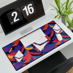 May include: A colorful abstract design mousepad with a white keyboard and a white mouse on top. The mousepad has a variety of colors, including red, blue, yellow, and purple. The design is abstract and geometric, with a variety of shapes and patterns.
