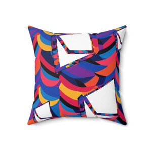 May include: A colorful throw pillow with a geometric pattern of overlapping shapes in shades of blue, red, yellow, purple, and black. The pillow has a white background with white geometric shapes.