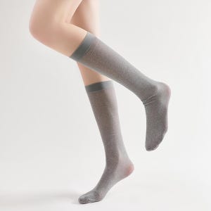 Pu&ograve; includere: Un paio di calze argentate con glitter alte al ginocchio con una fascia grigia in alto.