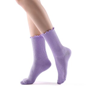 May include: A pair of lavender ribbed socks with a frilly edge. The socks are worn on a person's legs.